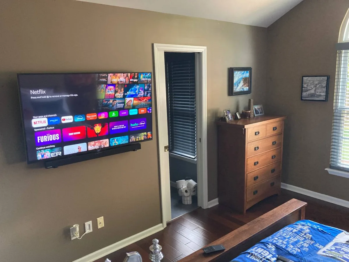 50-inch Sony Bravia TV mounted in bedroom with soundbar, Fire Stick setup, and streaming apps